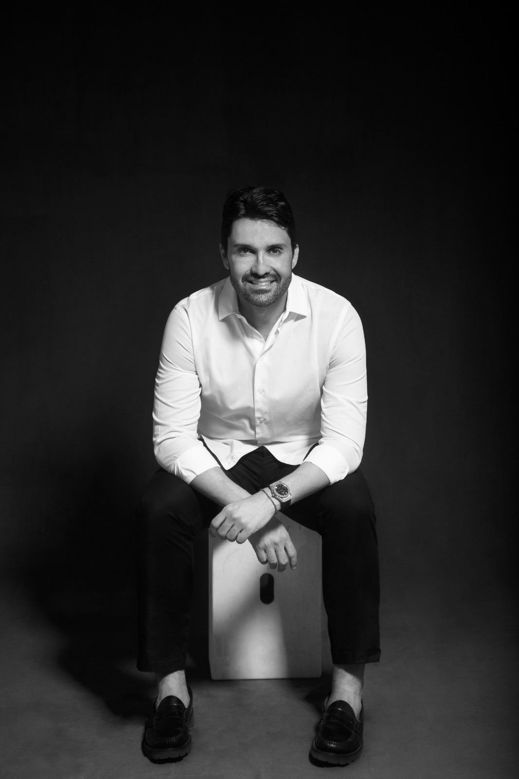 Retrato em preto e branco do designer de interiores Márcio Catão, sentado