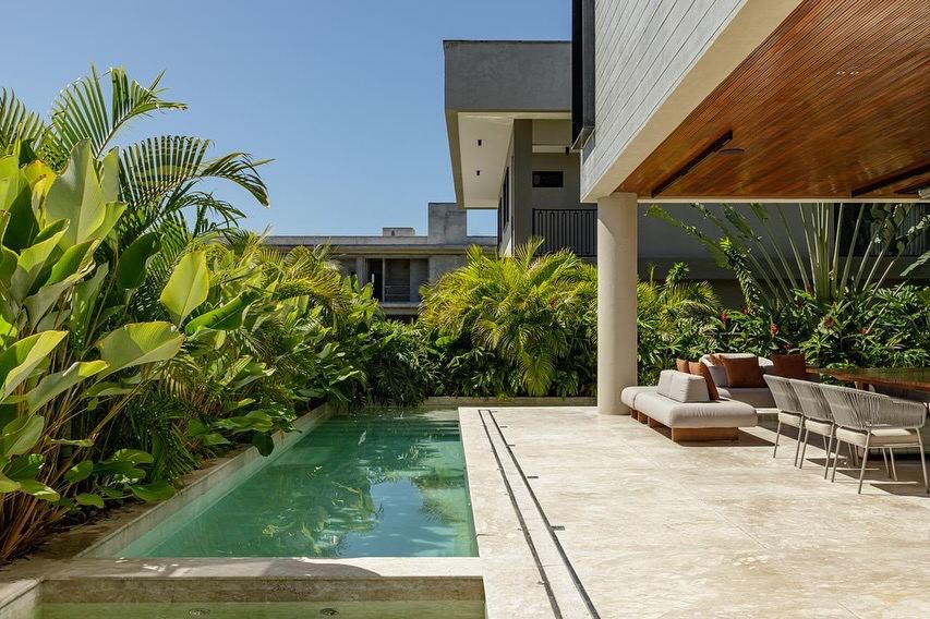 Piscina em meio a jardim tropical com deque e beiral de madeira